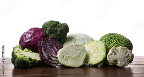 Different types of cabbage on wooden table against white background