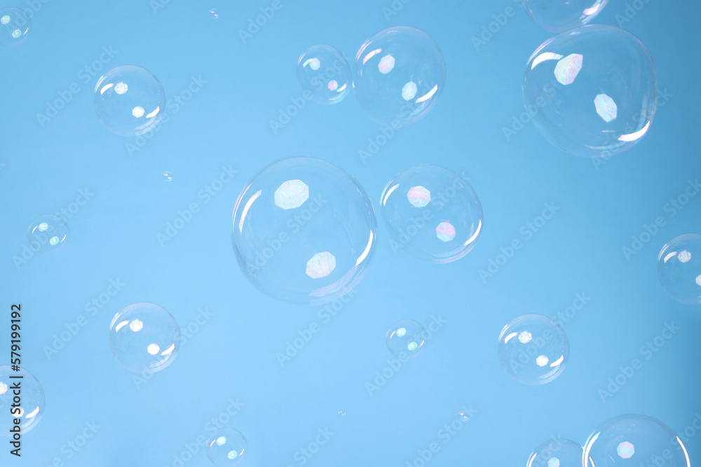 Many beautiful soap bubbles on light blue background. Space for text