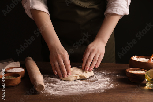 Woman making grissini at wooden table, closeup