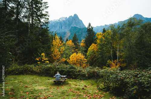 Woman sitting at a picnic table with with the view of Mount Index on the bavkground . Autumn leaves laying everywhere around.