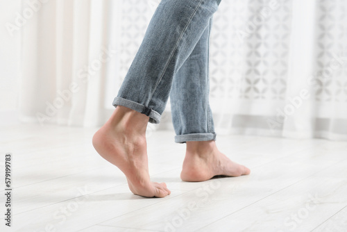 Barefoot woman walking on white parquet at home, closeup. Heated floor © New Africa