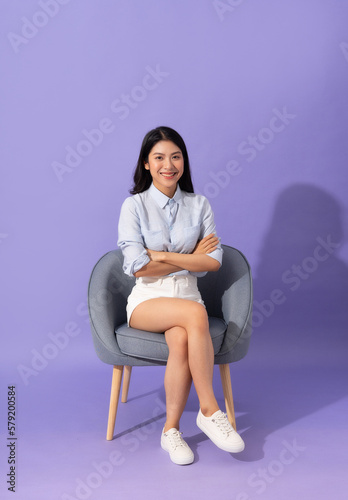 image of girl sitting on sofa isolated on purple background