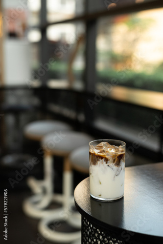 A glass of iced coffee sits on a table in a cafe.