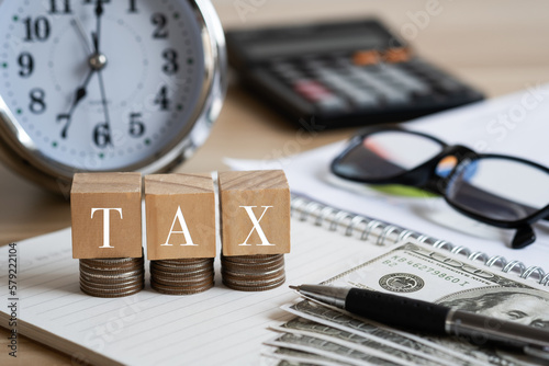 Tax words on wooden blocks and calculator with alarm clock. Tax concept.