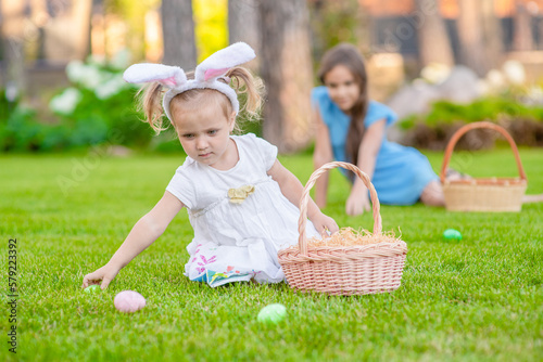 Group of happy kids hunt for Easter eggs on green grass