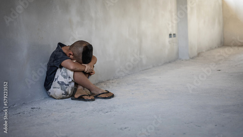 Obraz na plátně Homeless sad little child sitting alone on floor concrete wall background