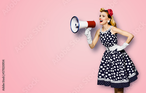 Portrait image of beautiful woman holding mega phone, shout advertising. Pretty girl in black pin up dress, white glows with megaphone loudspeaker. Isolated rose pink background. Big sales ad.