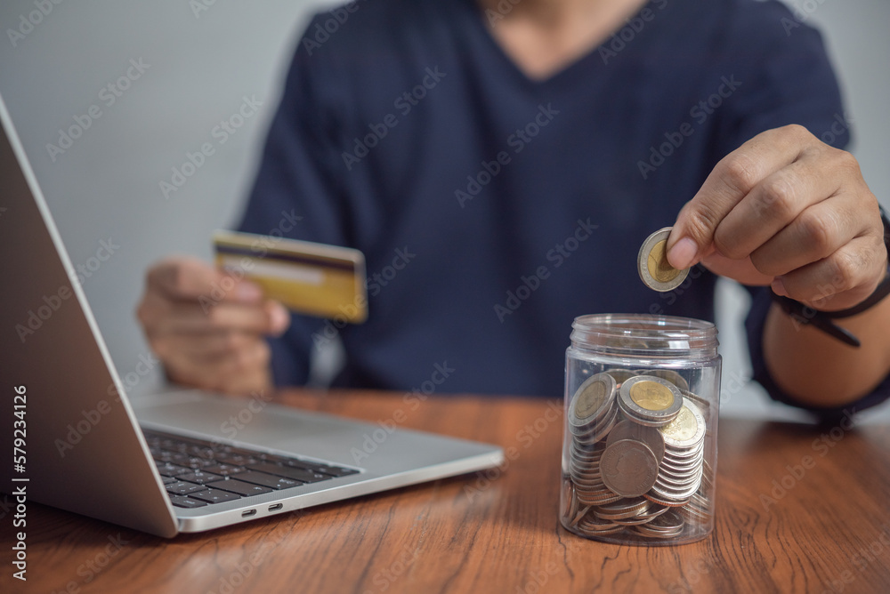 Fototapeta premium Man putting coin in jar. investment and money saving, banking and finance, online shopping on the internet, accounting and tax Business concept.