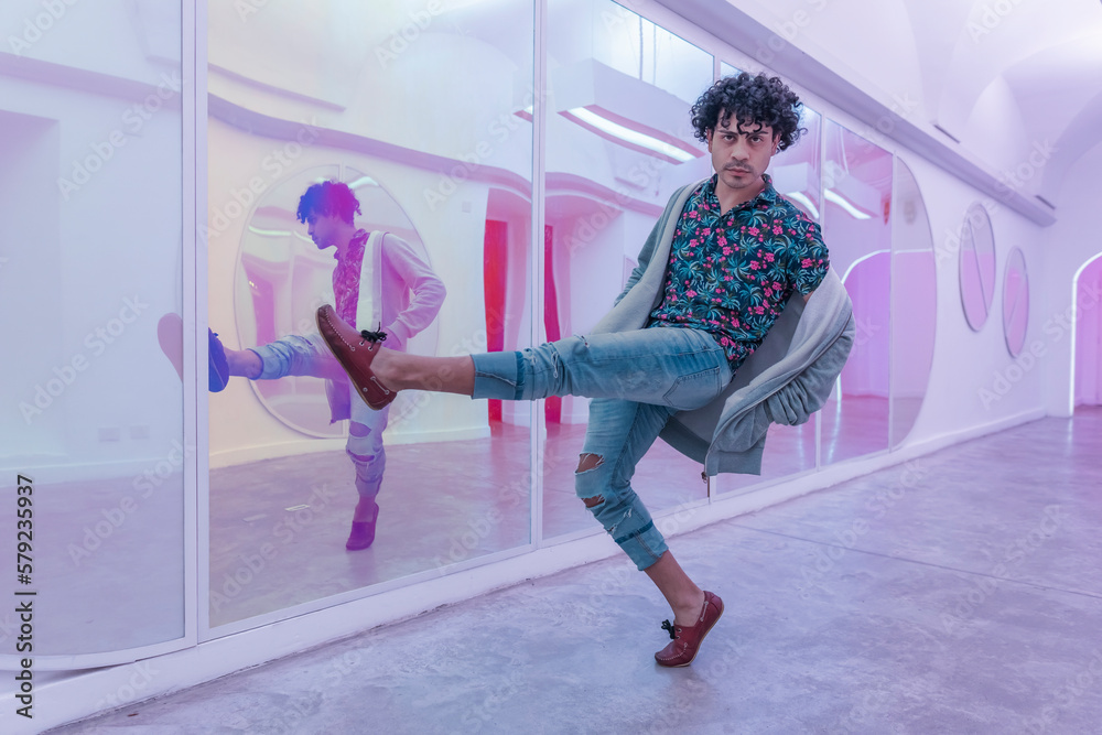 Young Latin homosexual guy Dancing Solo and looking at camera in a Mirrored room. Joyful and freedom lifestyle concept.