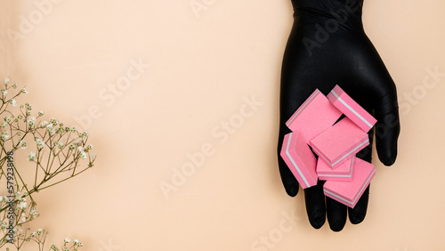 A set of manicure nail files with the same abrasive in the hand of the manicure master highlighted on a light background. Copying space photo