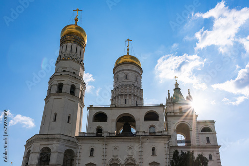 Ivan the Great Bell Tower, with Assumption Belfry on the right in Moscow Kremlin. Blue sky background with sunbeams