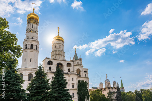 Ivan the Great Bell Tower, with Assumption Belfry on the right in Moscow Kremlin. Blue sky background with sunbeams