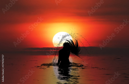 Silhouette of Woman in the sea at sunset flipping her hair out of the water