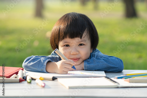 Print op canvas asian little girl drawing on paper in garden.