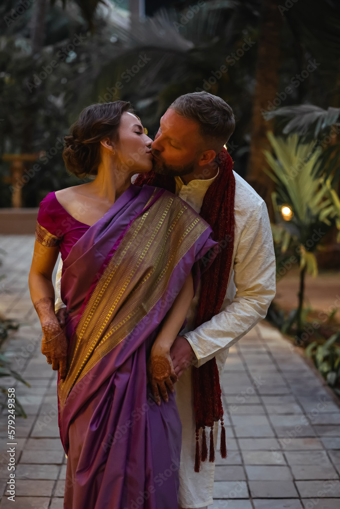 Wedding of a couple from Europe in India. A light skinned man in a traditional Indian men. white skin. Bride in beautiful sari with mehendi. Caucasian marriage. International couple.Lovely couple fit 