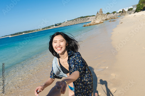 沖縄の海で恋人と走る女性