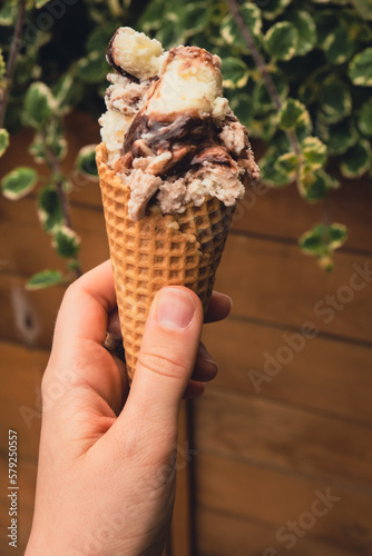 Female hand holding delicious american vanilla chocolate ice cream. Tasty homemade icecream Gelato in the waffle cone. Gluten free vegan dairy free ice cream. 