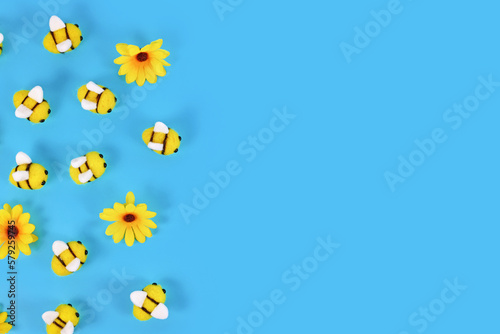 Fotografie, Obraz Cute felt bees and yellow flowers on side of blue background with copy space