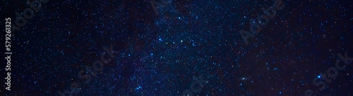 Astrophotography of a dark blue starry sky with many stars, nebulae and galaxies. Panoramic wide horizontal photo for banner head cover