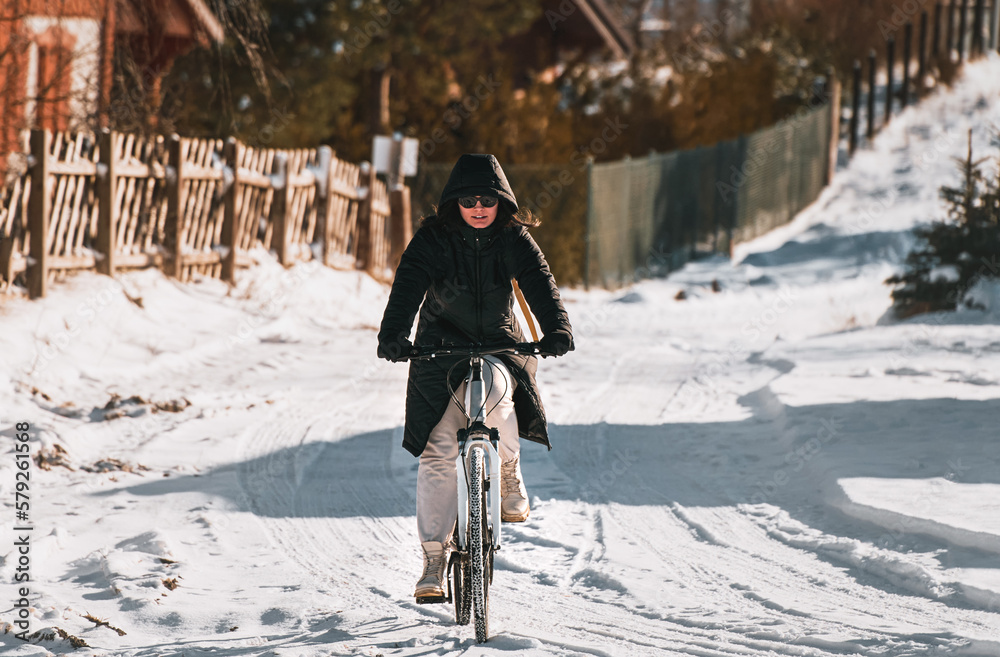 woman rides bicycle in winter snow