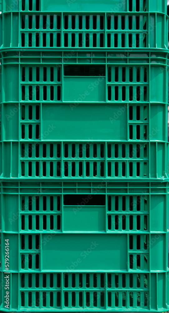 Green plastic crate boxes stacked outdoor under natural light Green plastic crate boxes stacked outdoor under natural light