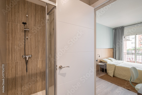 View from the small bathroom with shower onto the double bedroom with a window overlooking the balcony and courtyard. Concept of a respectable hotel room