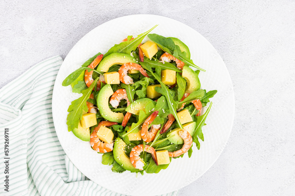 Flat lay of Healthy salad plate. Fresh seafood recipe. Grilled shrimps and fresh vegetables (avocado, arugula, mango) on gray concrete background. Flat lay of Healthy salad plate. Fresh seafood recipe. Grilled shrimps and fresh vegetables (avocado, arugula, mango) on gray concrete background.