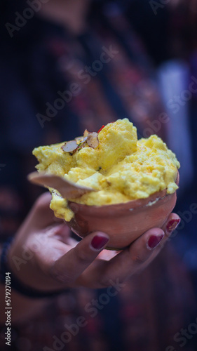 Bokeh shot of winter dessert Malaiyo at road side shops in Varanasi. Street food of Varanasi in the form of cream foam called Malleyoo with pista and dry fruit toppings, served in mud made pot.
 photo