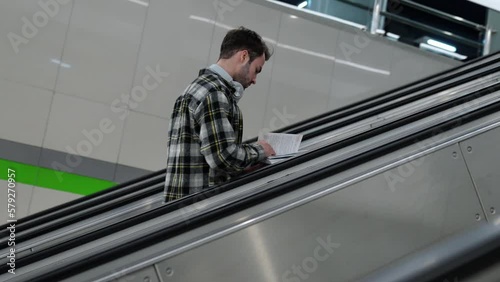 Wallpaper Mural Handheld, focused student rides an escalator in the subway while reading a book, young man goes to study at the university. Torontodigital.ca
