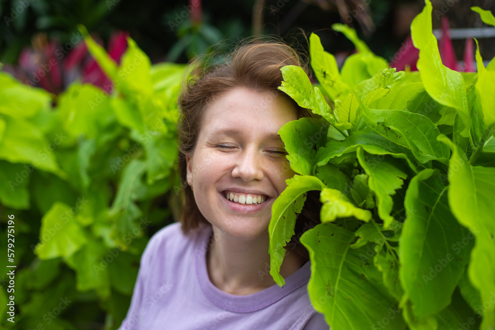young woman smiling in nature in the park, on a green wall background, in her garden, in spring or summer young woman smiling in nature in the park, on a green wall background, in her garden, in spring or summer
