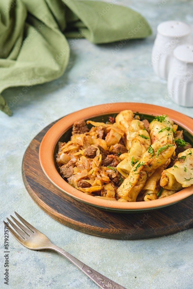 Ragout, stewed beef with cabbage and dough dumplings in a ceramic plate on a light concrete background. Cabbage recipes. Ragout, stewed beef with cabbage and dough dumplings in a ceramic plate on a light concrete background. Cabbage recipes.