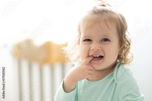 toddler girl smile and puts finger in mouth, authentic joy, bright concept
