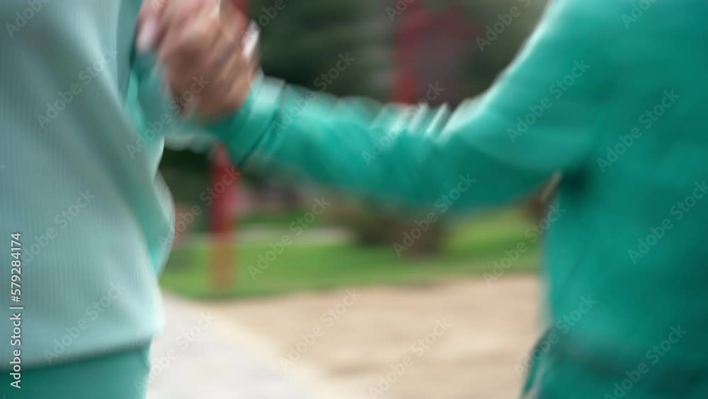 Cheerful adult and senior women running with girl holding hands having fun in park. Live camera follows joyful Caucasian multigenerational family enjoying leisure