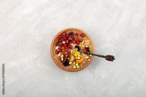 Ashure Dessert, Ashura or Anusabur on grey background, top view. Turkish delicious porridge with grains, fruits, and nuts. Sweet pudding also called as Noah's pudding or Noah's Dessert