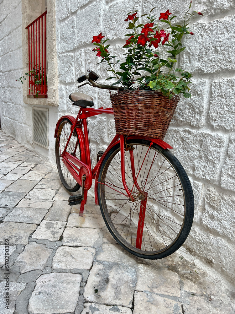 bicycle with red flowers in front of a brick wall