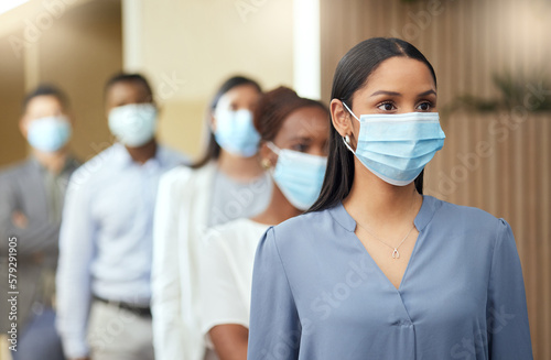 Its a question of health and safety. Cropped shot of an attractive young businesswoman wearing a mask while standing at the head of a queue in her office.