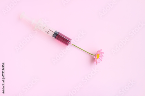 Injection Syringe with Pink Chrysanthemum flower on pink background, Beauty injections concept.