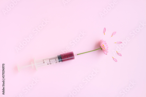 Injection Syringe with Pink Chrysanthemum flower on pink background, Beauty injections concept.