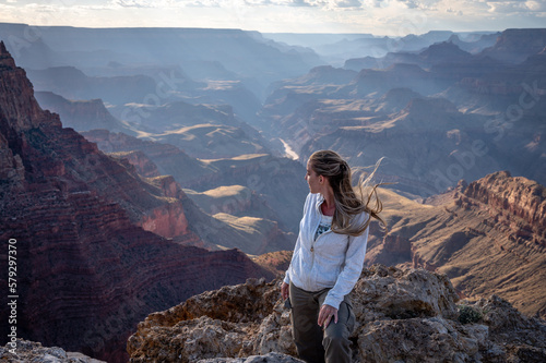 A young blonde girl standing on the edge of the precipice of the grand canyon looking at the landscape