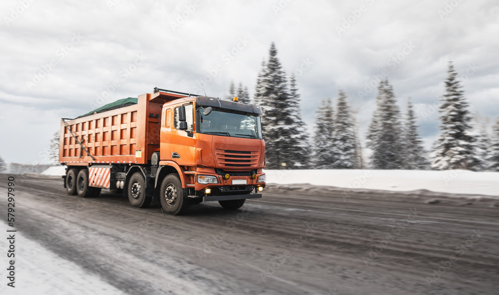 Large quarry dump truck. Dump truck carrying coal, sand and rock. Trucks moving on dirt country road in forest. Mining truck mining machinery to transport coal from open-pit. Transportation of mineral