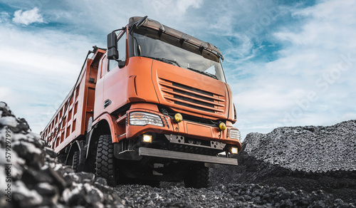 Large quarry dump truck. Dump truck carrying coal, sand and rock. Trucks moving on dirt country road in forest. Mining truck mining machinery to transport coal from open-pit. Transportation of mineral