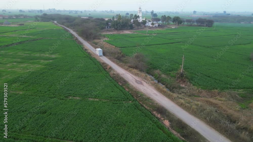 vehicle moving front in crop fields wide side view