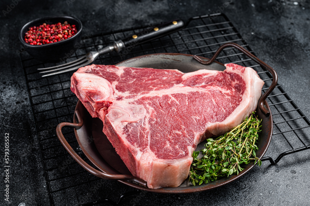 Fresh raw T-bone marbled beef meat Steak on a steel tray. Black background. Top view