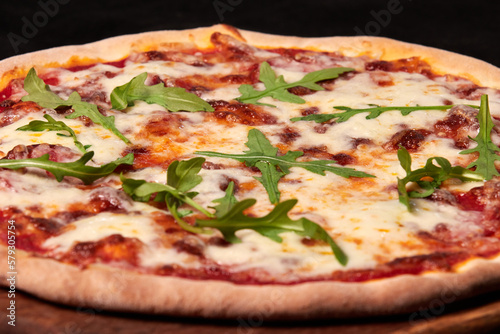 Delicious traditional Italian Margarita pizza with cheese, tomato sauce and herbs on a wooden board