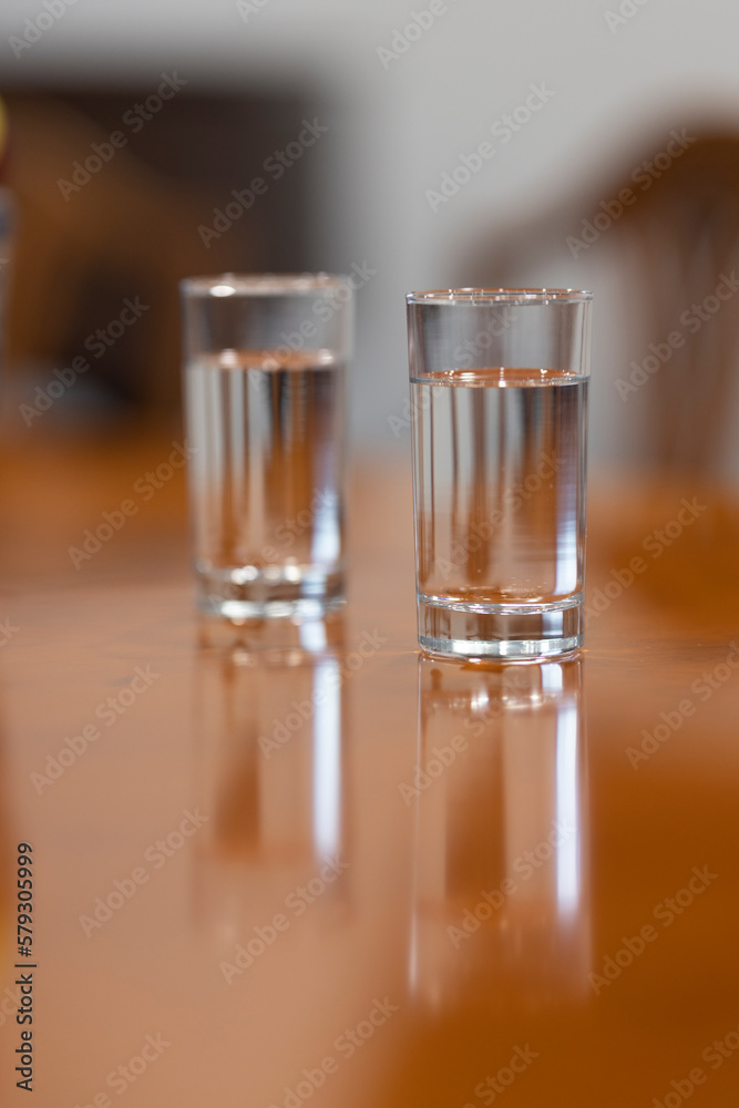 Two glasses full of water on a brown table Two glasses full of water on a brown table