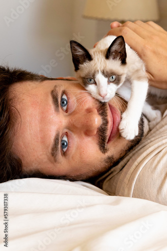 Portrait of happy cat and caucasian man with blue eyes . Handsome young animal-lover man hugs his cat. Sweet and mellow kitty