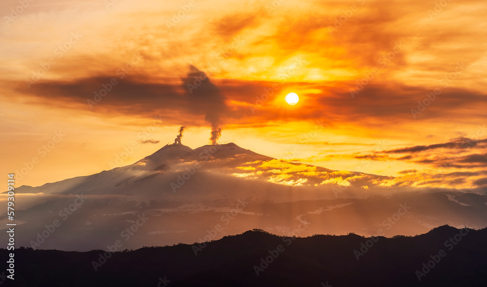 mysterious landscape of great erupting volcano with smoke from craters and snow on slopes in orange light of sunset. eruption of vulcan mysterious landscape of great erupting volcano with smoke from craters and snow on slopes in orange light of sunset. eruption of vulcan