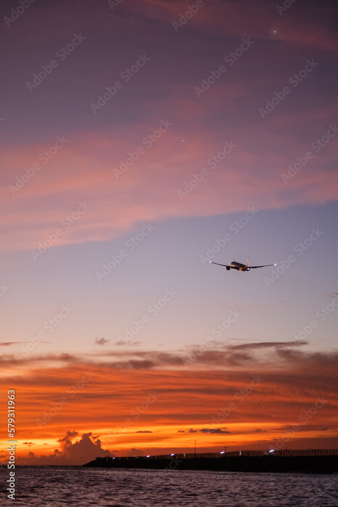 Commercial airplane landing over ocean at sunset with vibrant sky, scenic aviation travel photography. Commercial airplane landing over ocean at sunset with vibrant sky, scenic aviation travel photography.