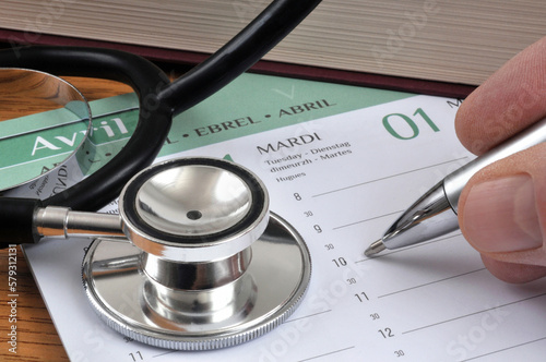 Concept de prise de rendez-vous médical sur un agenda avec un stylo en main et un stéthoscope