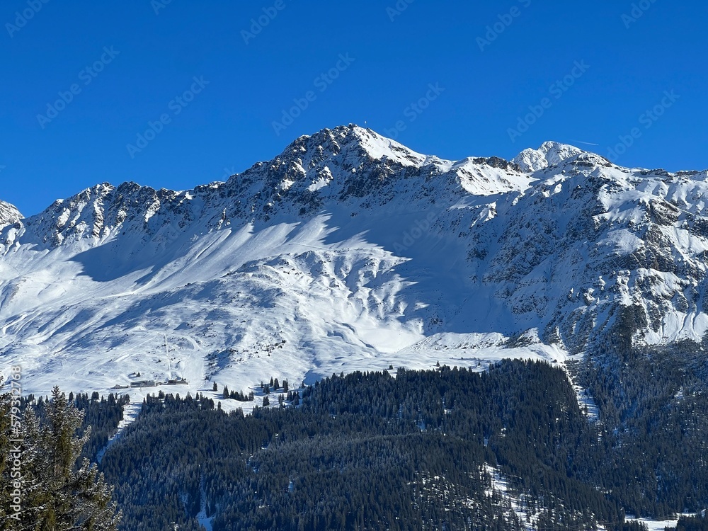 Beautiful sunlit and snow-capped alpine peaks above the Swiss tourist sports-recreational winter resorts of Valbella and Lenzerheide in the Swiss Alps - Canton of Grisons, Switzerland (Schweiz)